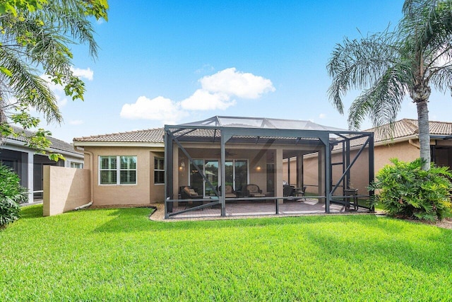 back of property with a yard, glass enclosure, and a patio area