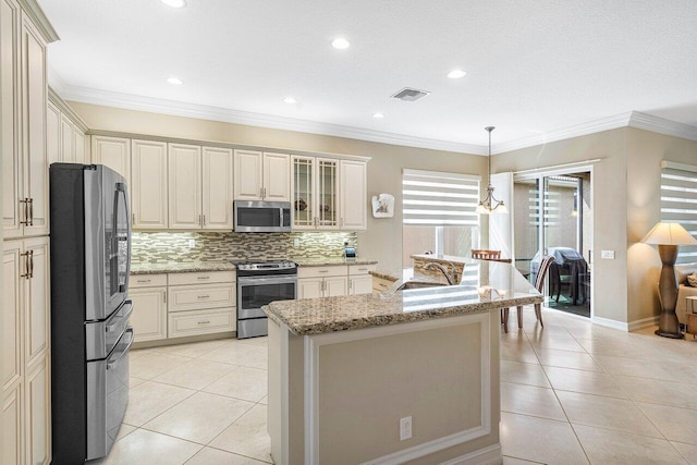 kitchen featuring light stone counters, pendant lighting, a kitchen island with sink, stainless steel appliances, and crown molding