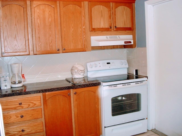 kitchen featuring white electric range oven, decorative backsplash, dark stone counters, and extractor fan