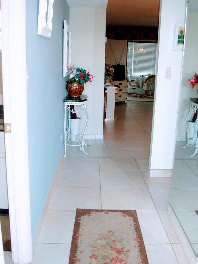 hall with beamed ceiling and light tile patterned floors