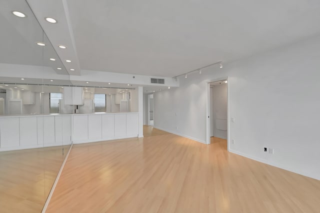 unfurnished living room featuring light wood-type flooring and rail lighting