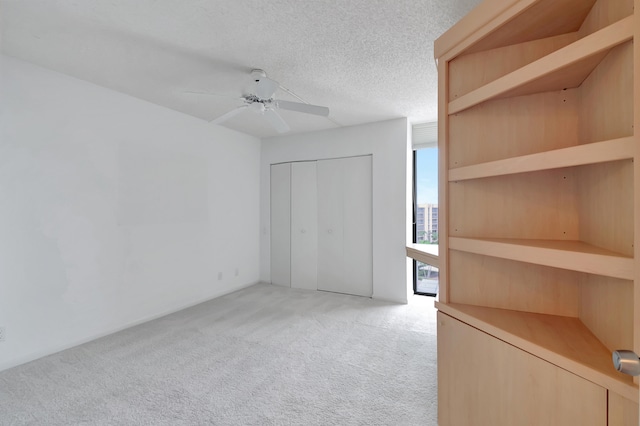 unfurnished bedroom with a textured ceiling, ceiling fan, a closet, and light colored carpet