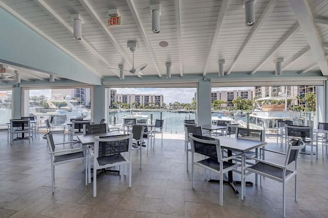 dining room with a water view, wooden ceiling, vaulted ceiling with beams, and ceiling fan