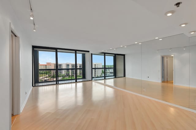 empty room with a wall of windows and light wood-type flooring