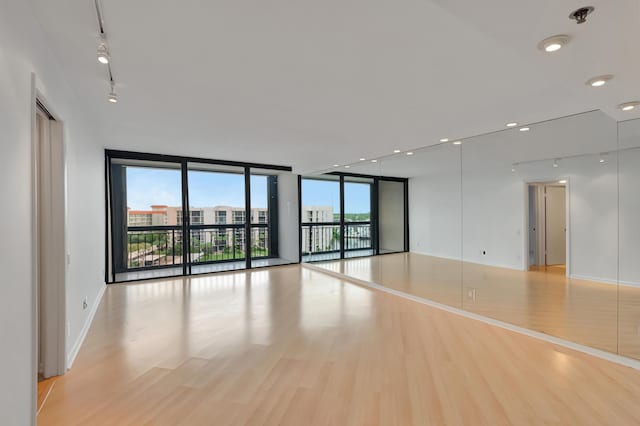 spare room featuring floor to ceiling windows, recessed lighting, light wood-style floors, and baseboards