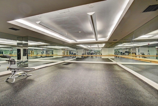 gym with a textured ceiling and a raised ceiling