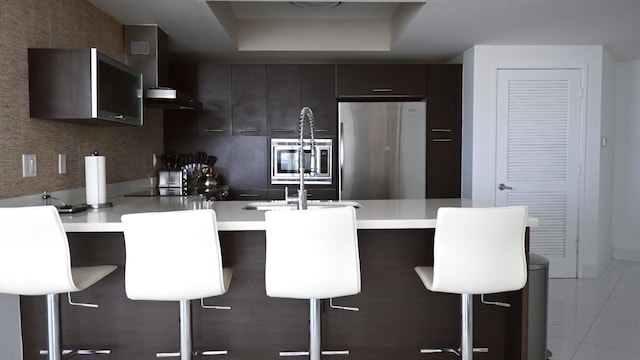 kitchen featuring stainless steel refrigerator, a kitchen breakfast bar, light tile patterned floors, and kitchen peninsula