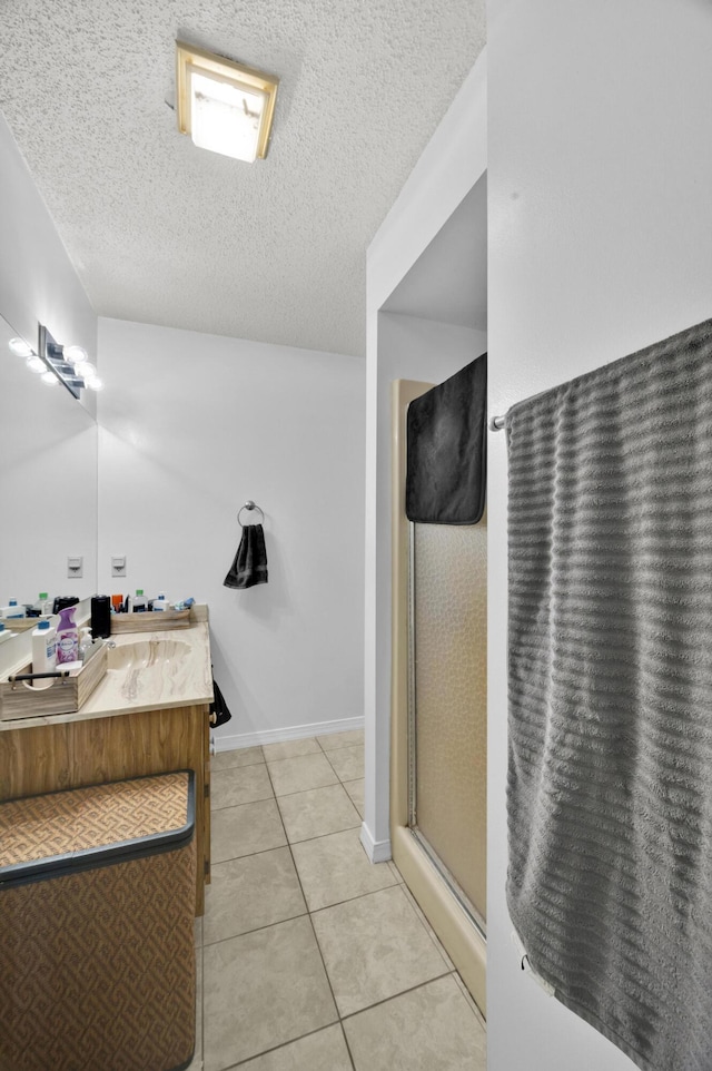 bathroom featuring vanity, a textured ceiling, walk in shower, and tile patterned flooring