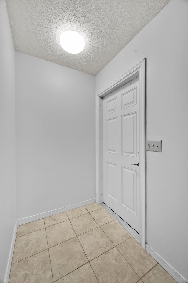 interior space with a textured ceiling and light tile patterned floors