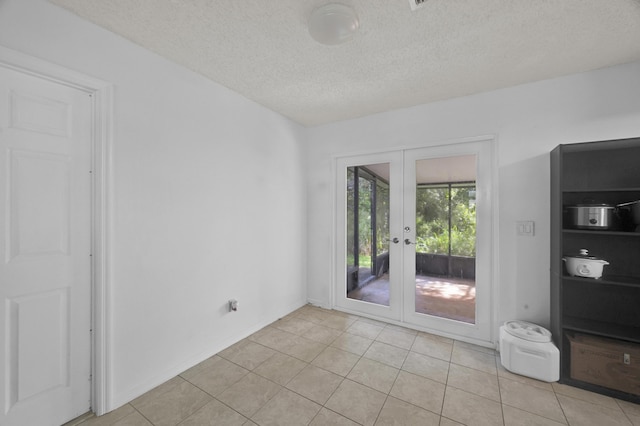 empty room with french doors, a textured ceiling, and light tile patterned floors