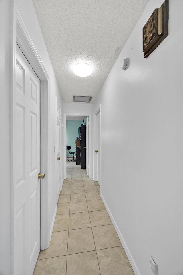 5000 Fort Pierce Blvd, Fort Pierce, FL 34951 - hallway with a textured ceiling, a desk, light tile patterned flooring, and baseboards