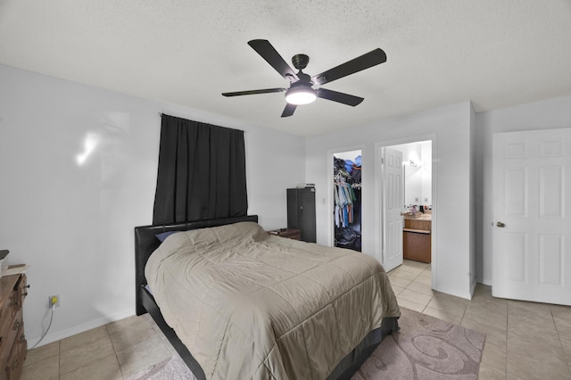 bedroom with ceiling fan, a textured ceiling, connected bathroom, a closet, and a walk in closet