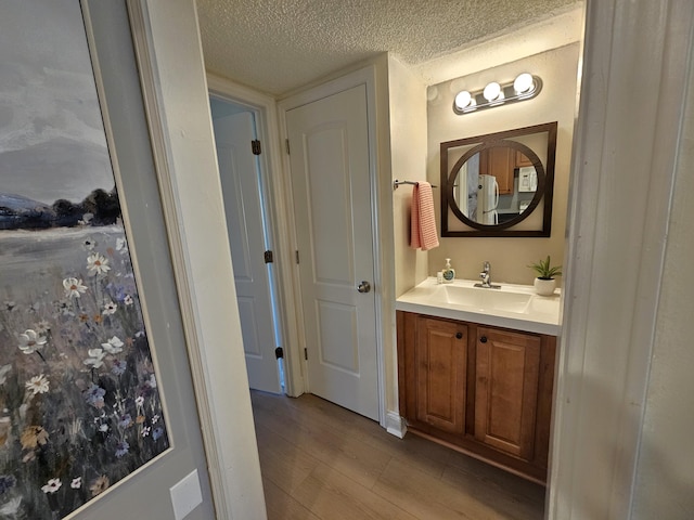 bathroom with vanity, wood finished floors, and a textured ceiling