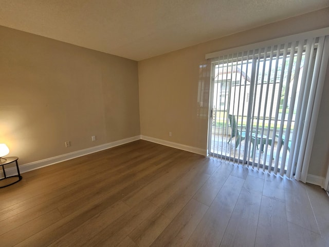 spare room featuring dark wood-type flooring and baseboards