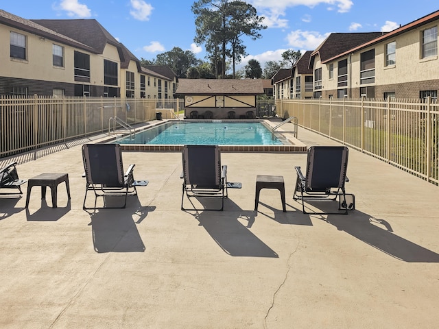 community pool featuring a residential view, fence, and a patio area