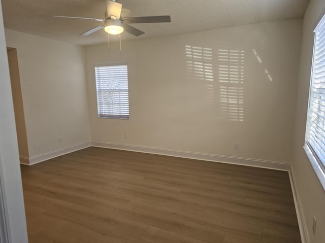 unfurnished room with dark wood-style floors, baseboards, and ceiling fan