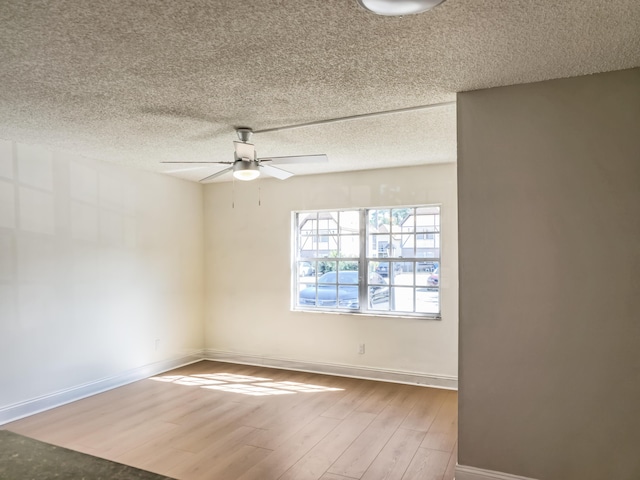 empty room featuring a textured ceiling, wood finished floors, baseboards, and ceiling fan