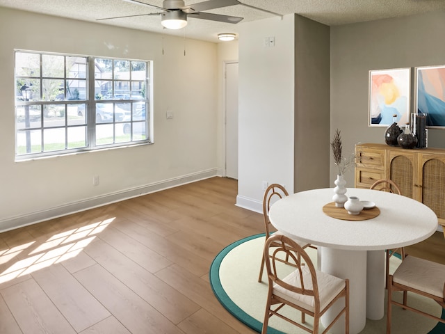 dining space featuring baseboards, wood finished floors, a textured ceiling, and ceiling fan