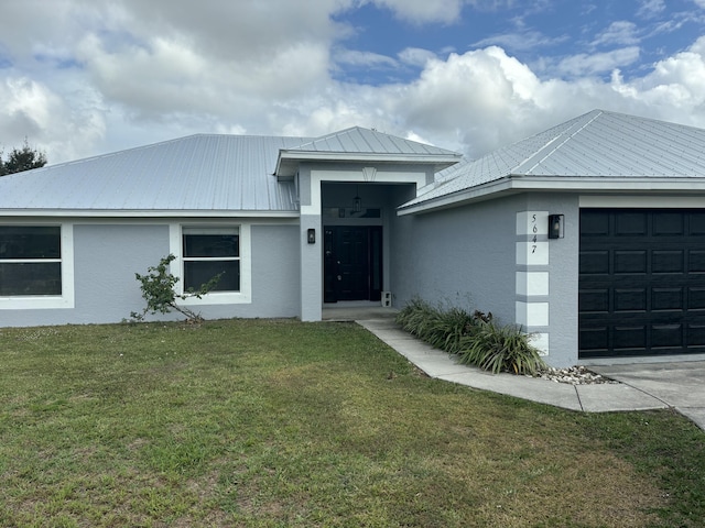 view of front of house with a garage, a front yard, metal roof, and stucco siding