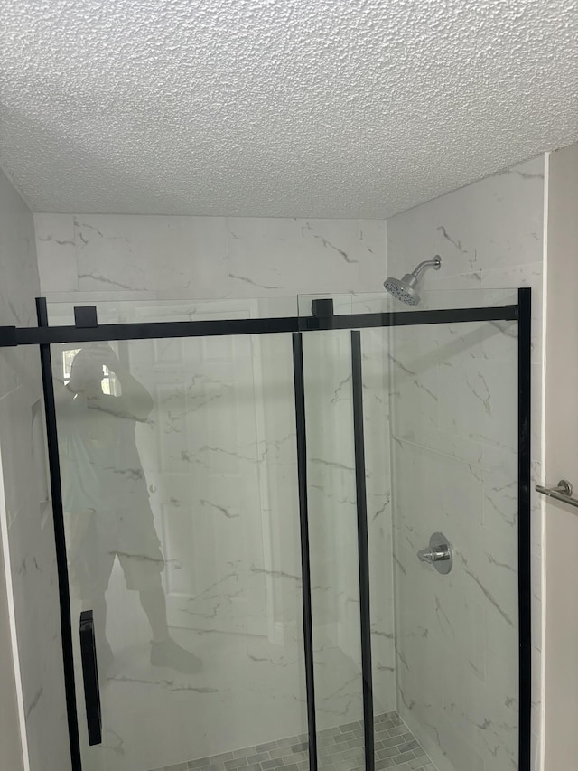 bathroom with a textured ceiling and a marble finish shower