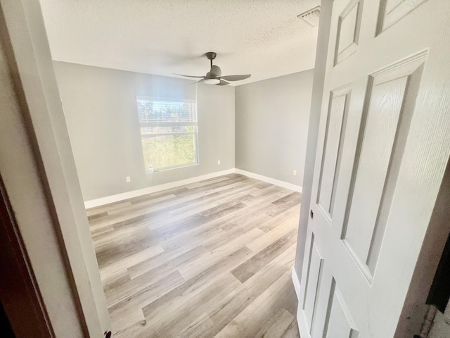 unfurnished bedroom with light wood-style flooring, baseboards, ceiling fan, and a textured ceiling