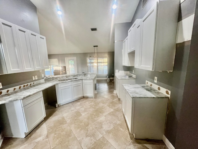 kitchen featuring white cabinetry, kitchen peninsula, washer / clothes dryer, pendant lighting, and vaulted ceiling