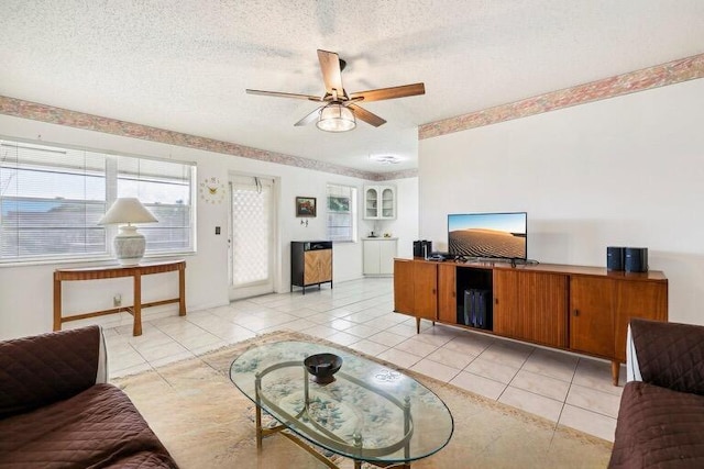 living room featuring ceiling fan, light tile patterned floors, and a textured ceiling