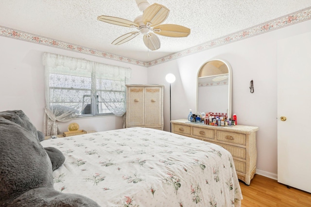 bedroom with ceiling fan, a textured ceiling, and light wood-type flooring