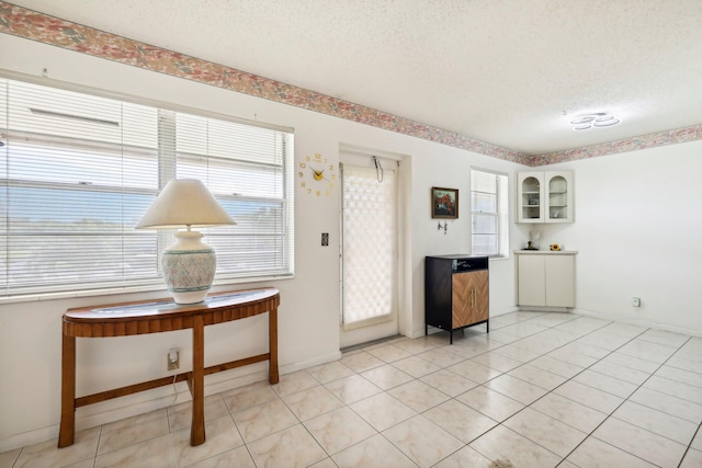 foyer entrance with a textured ceiling and light tile patterned floors