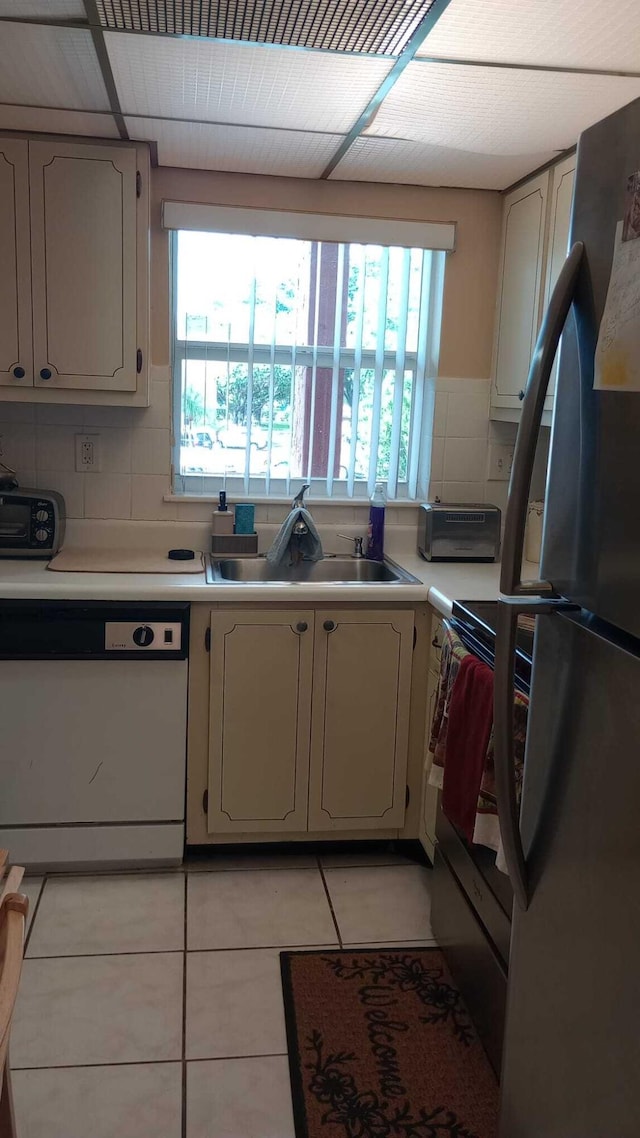 kitchen featuring dishwasher, decorative backsplash, stainless steel fridge, sink, and light tile patterned floors