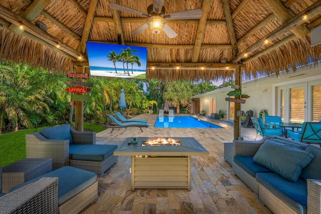 view of pool featuring ceiling fan, a patio, and an outdoor living space with a fire pit