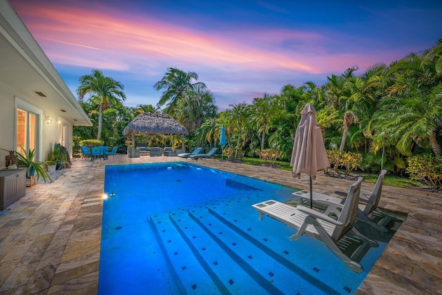 pool at dusk featuring a patio area and a gazebo