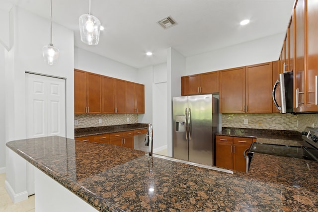 kitchen with pendant lighting, dark stone counters, tasteful backsplash, kitchen peninsula, and stainless steel appliances