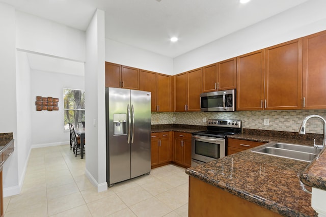 kitchen featuring light tile patterned floors, sink, tasteful backsplash, stainless steel appliances, and dark stone countertops