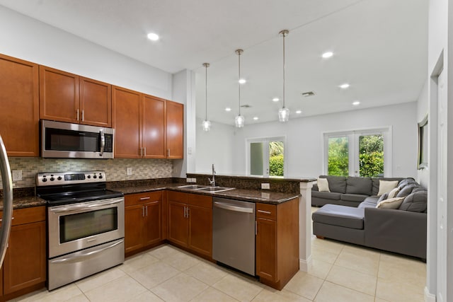 kitchen with dark stone counters, sink, hanging light fixtures, stainless steel appliances, and light tile patterned floors