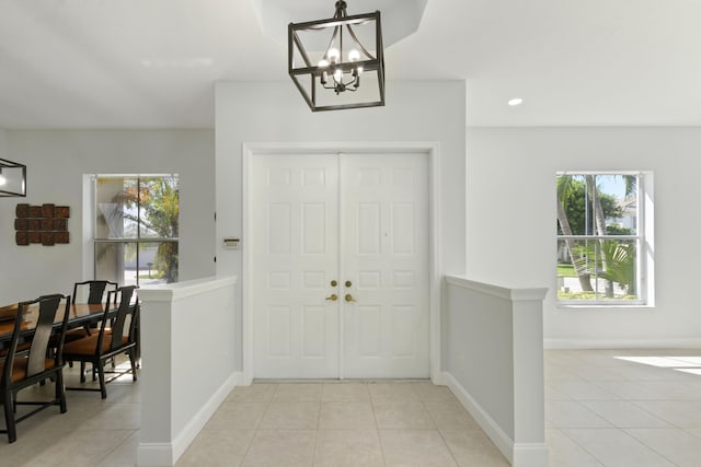 tiled entryway featuring a healthy amount of sunlight and a notable chandelier