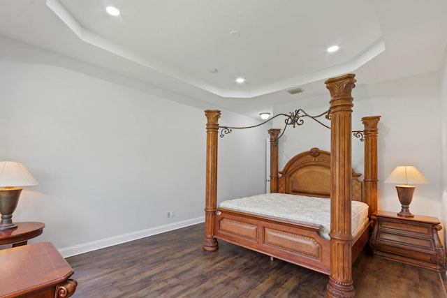 bedroom with a tray ceiling and dark hardwood / wood-style floors