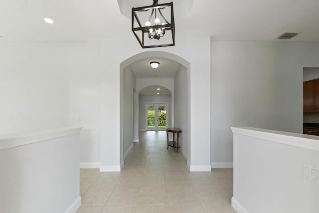 corridor with light tile patterned flooring and a chandelier