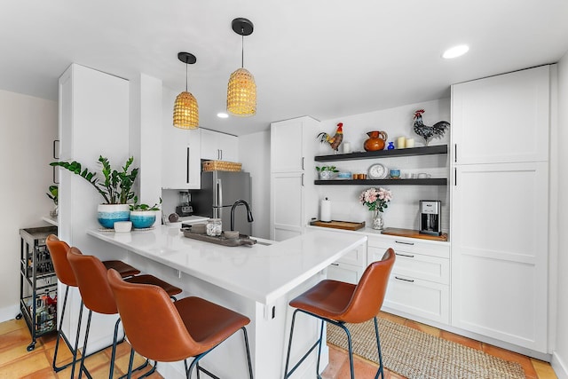 kitchen featuring white cabinets, a kitchen breakfast bar, hanging light fixtures, and kitchen peninsula