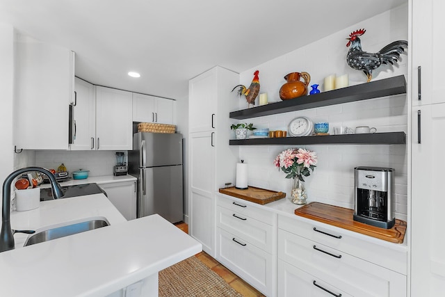 kitchen with white cabinets, stainless steel refrigerator, sink, and tasteful backsplash