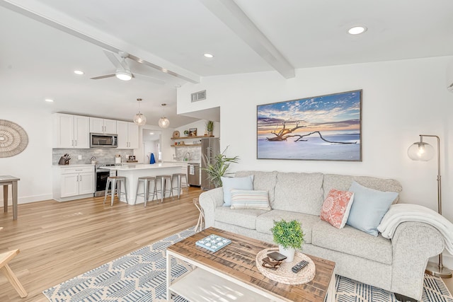 living room featuring ceiling fan, lofted ceiling with beams, and light hardwood / wood-style flooring