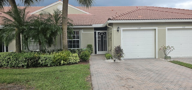 view of front of property with an attached garage, stucco siding, a tile roof, and decorative driveway