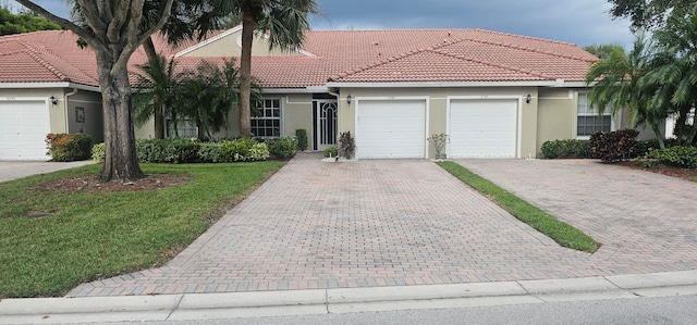 ranch-style house with stucco siding, a tiled roof, an attached garage, and decorative driveway