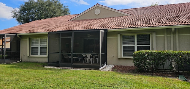 back of property with a lawn and a sunroom