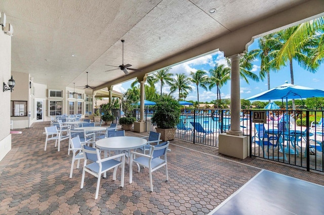 view of patio with ceiling fan, fence, outdoor dining area, and a community pool