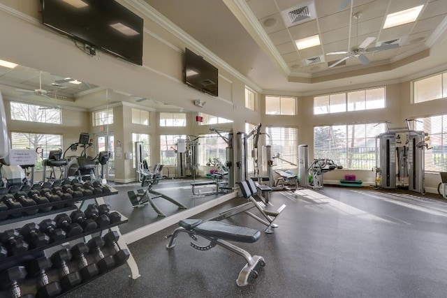 gym featuring a tray ceiling, crown molding, visible vents, and ceiling fan