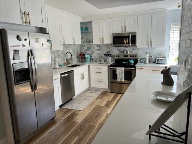 5324 Fountains Dr S, Lake Worth, FL 33467 - kitchen with open shelves, light wood-style floors, light countertops, a sink, and stainless steel appliances