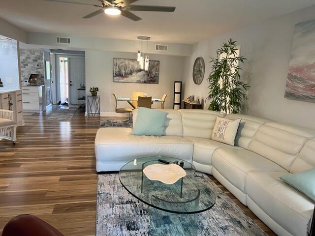 living room featuring dark wood-type flooring and ceiling fan