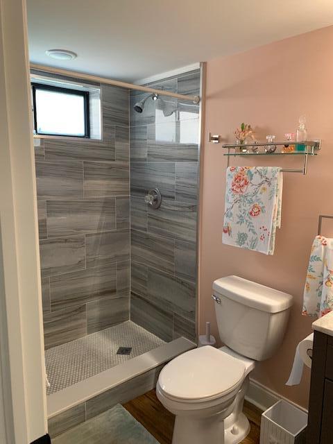 bathroom with vanity, toilet, and a tile shower