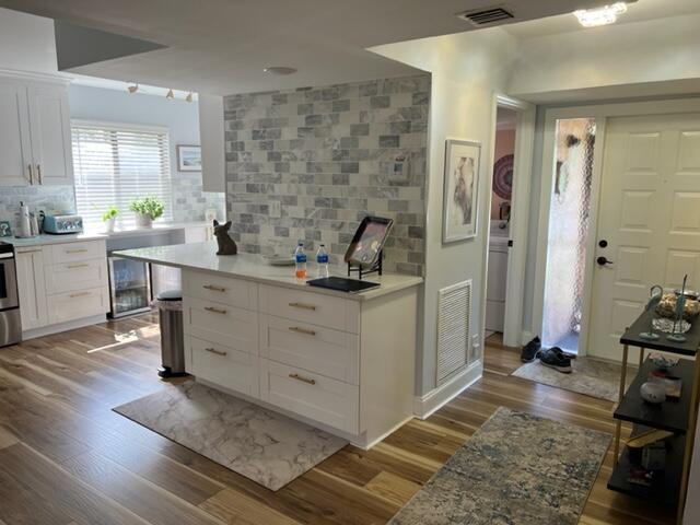 kitchen with tasteful backsplash, light stone counters, white cabinetry, and light hardwood / wood-style floors